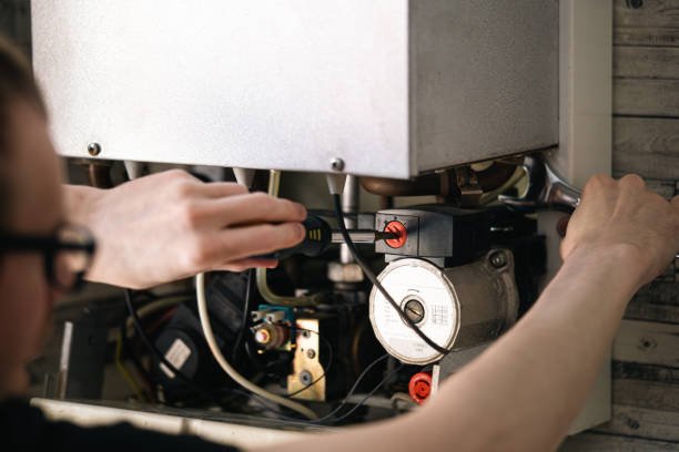 Man is repairing a heating boiler, a screwdriver and a spanner in his hands, copy space.