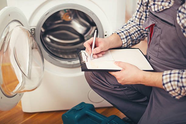 Repairman is repairing a washing machine on the white background. Entering malfunction